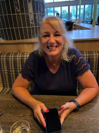 a woman sitting at a table holding a cell phone