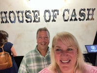 two people standing in front of a house of cash sign