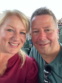 a man and woman taking a selfie at a baseball game