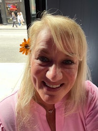 a woman wearing a pink shirt with a flower in her hair