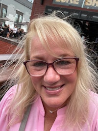 a woman wearing glasses and a pink shirt