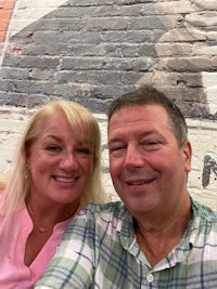 a man and woman taking a selfie in front of a brick wall